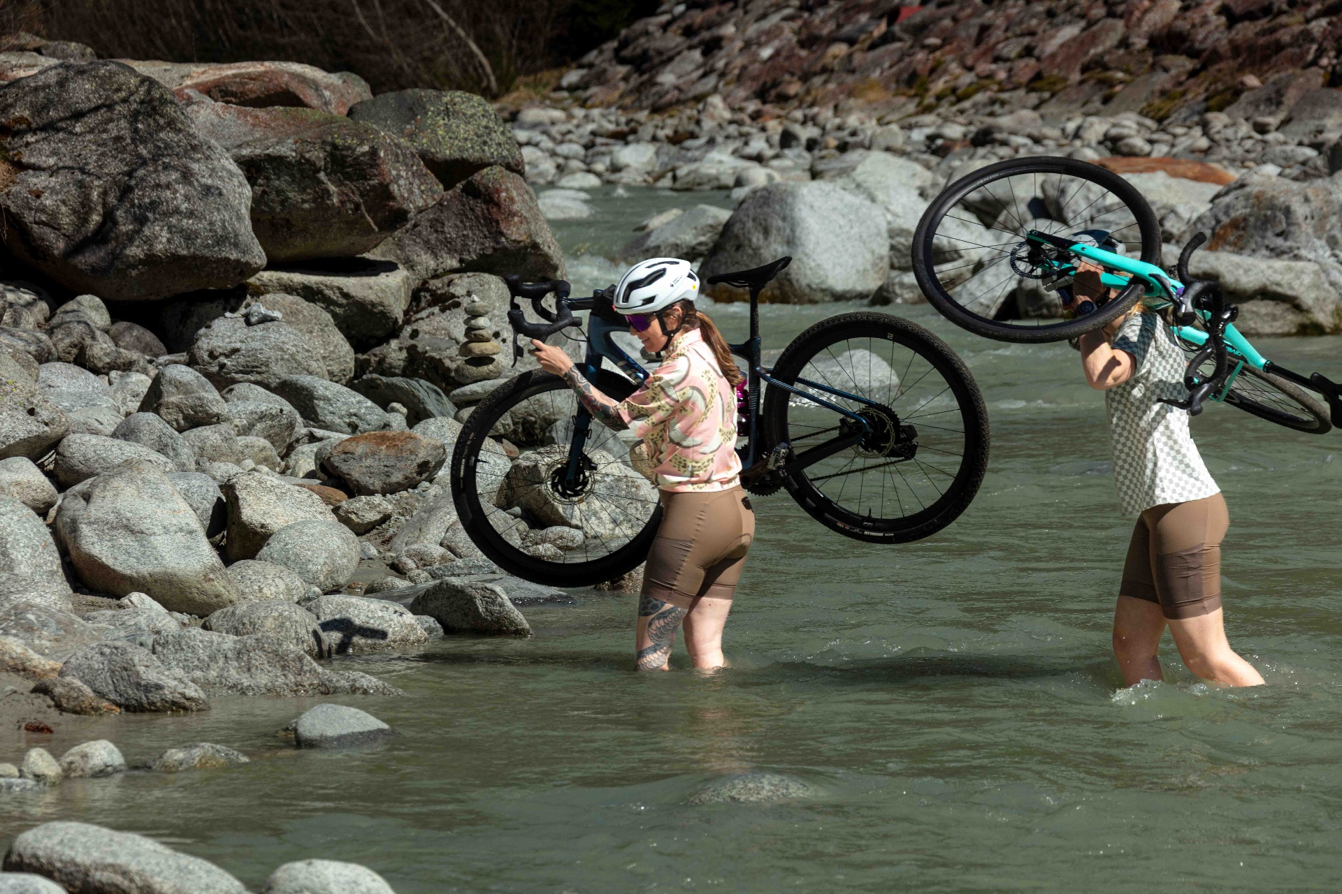 Deux cyclistes GLOW traversant une rivière avec leurs vélos